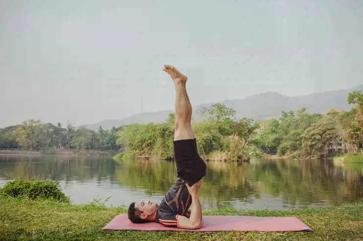 Man in a yoga pose enjoying the view of a peaceful lake