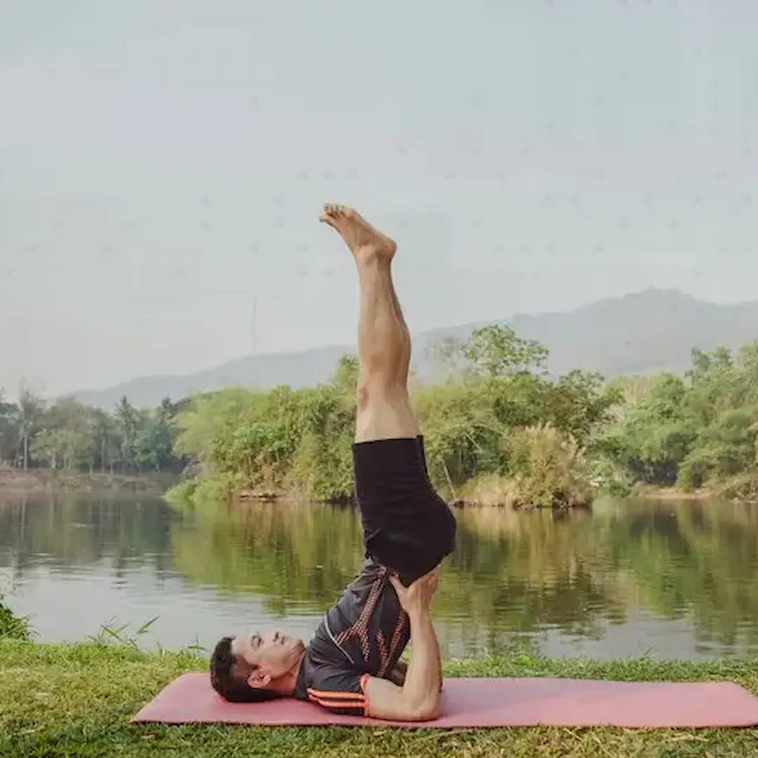 Man in a yoga pose enjoying the view of a peaceful lake